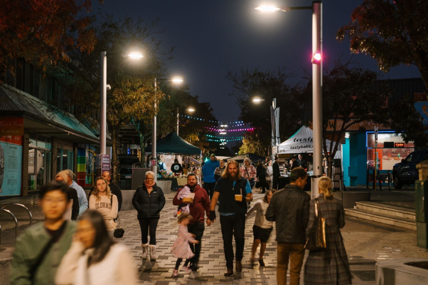 people walking through a twilight arket at dusk past a number of stalls